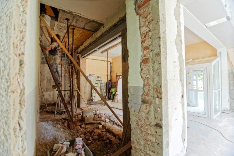 Chantier de rénovation d’un appartement ancien, murs en pierre et brique mis à nu, artisan au travail